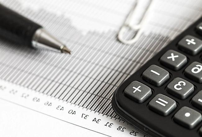 A calculator and pen sit on top of a piece of paper.